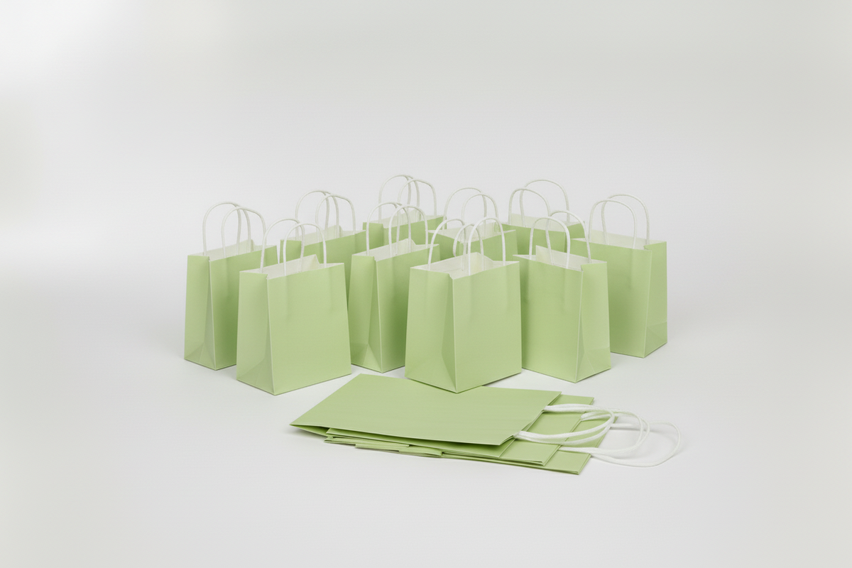 A set of light green paper shopping bags with white twisted paper handles, arranged on a seamless light gray studio background.