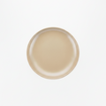 A minimalist, top-down view of a round ceramic plate in a warm beige color, centered on a clean white background.