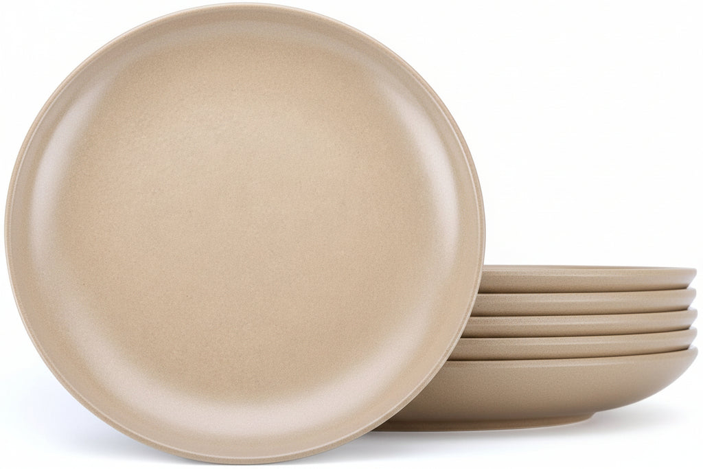 A set of matte beige ceramic plates, with one large plate standing upright in front of a stack of five smaller plates, on a clean white background.