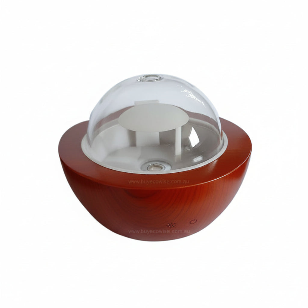 A modern tabletop diffuser with a glossy reddish-brown base, a clear acrylic dome lid, and a white interior diffuser visible through the dome, set against a plain white background.