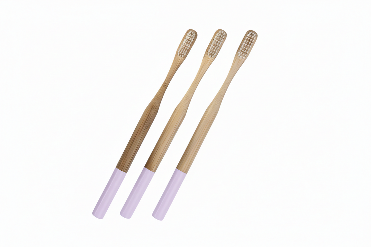 Three bamboo toothbrushes with light purple handles, arranged diagonally on a solid white background.